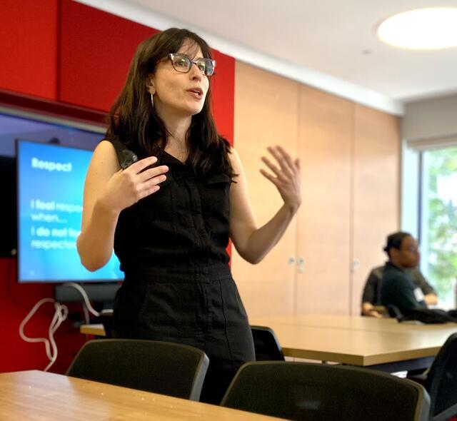 Woman talking and standing in front of slide presentation