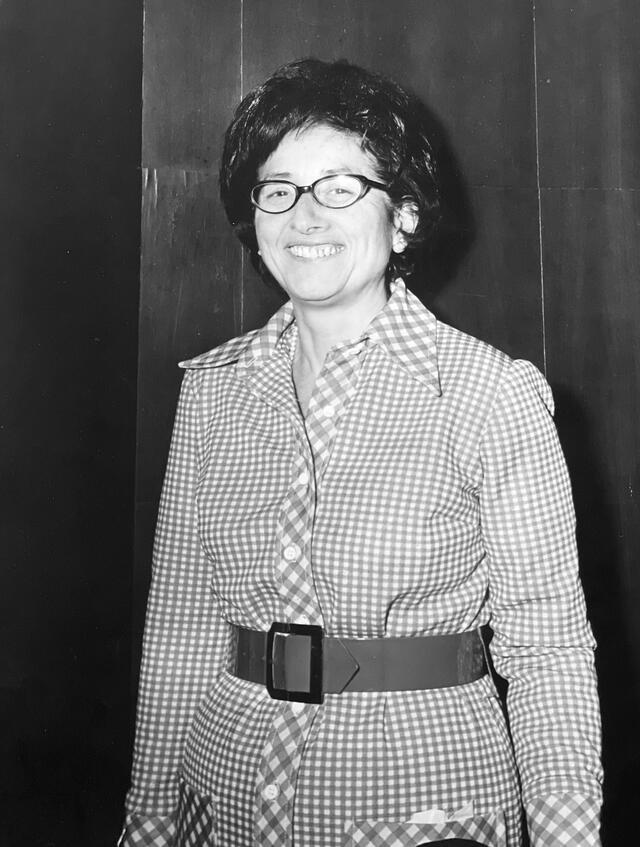 black and white photograph of a woman with short dark hair wearing a checked dress