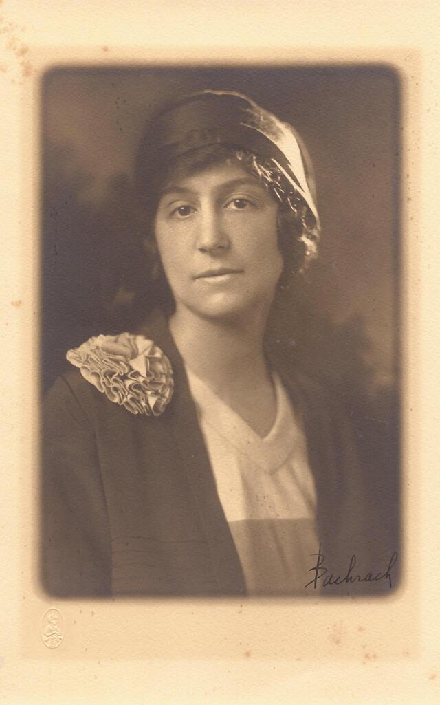 black and white photograph of a woman with a hat and a rosette on her shoulder