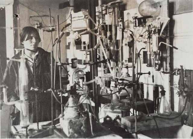 black and white photograph of a woman in a lab surrounded by lab equipment