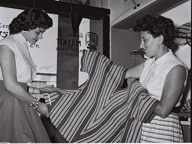 black and white photograph of two women holding a textile