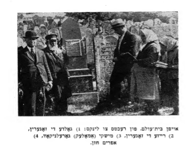 black and white photograph with two women in white head scarves with prayer books and three men in a cemetery
