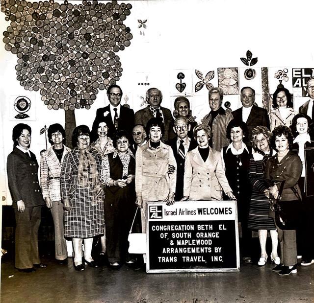 Black-and-white photo of a group of people with a sign reading "El Al Israel Airlines Welcomes Congregation Beth El South Orange"