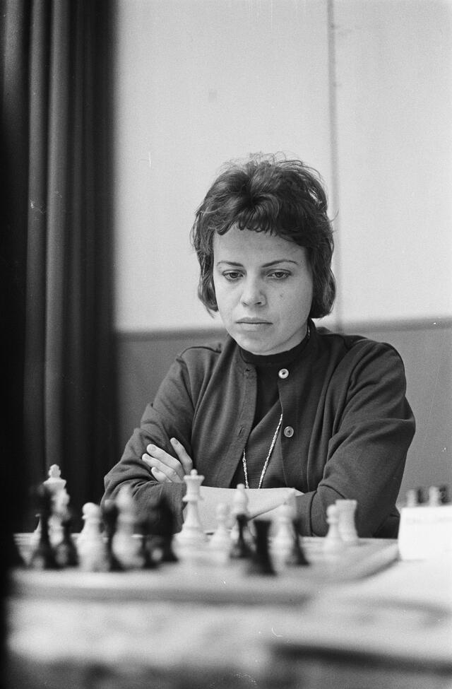 black and white photograph of a woman with short dark hair playing chess