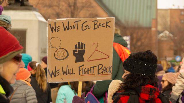Someone holding a sign that reads "We won't go back. We will fight back."